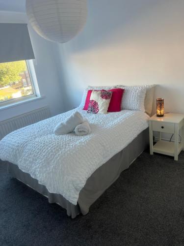 a bedroom with a bed with pink pillows and a window at Coastal Corporate Stays in Blythe