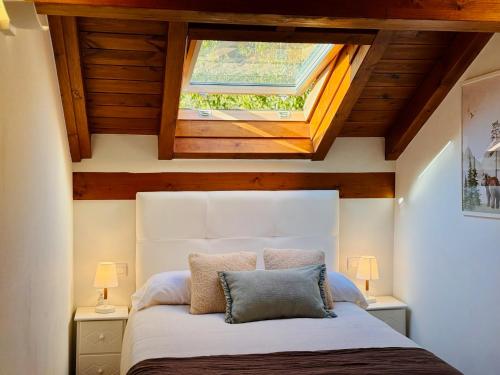 a bedroom with a large bed with a skylight at Apartamento Acogedor con Vistas Espectaculares en Liébana, Picos de Europa in Camaleño