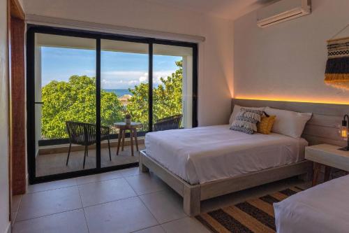 a bedroom with a bed and a large window at Bayshore 76 Beachfront Villa Palmar de ocoa in Palmar de Ocoa