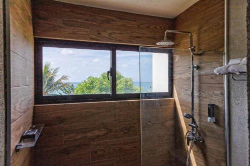 a bathroom with a glass shower with a window at Bayshore 76 Beachfront Villa Palmar de ocoa in Palmar de Ocoa