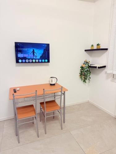 a table and chairs with a tv on a wall at Casa AntoLeo - Borgo Casale Vicenza Centro in Vicenza