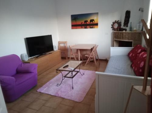 een woonkamer met een paarse bank en een tafel bij Casa al mare in centro a 100 metri dalla spiaggia con terrazza in Torre Santa Sabina