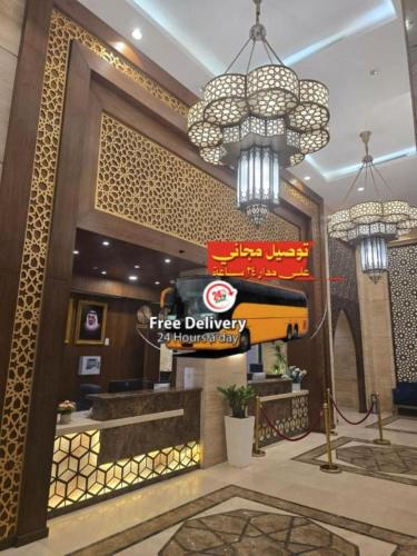 a restaurant lobby with a first delivery sign and chandeliers at Manazel Al Ain Ajyad Hotel in Makkah