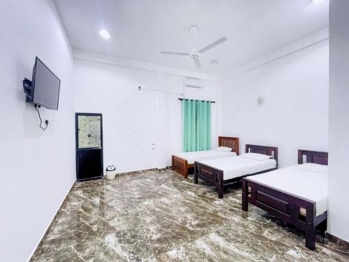 een kamer met 2 bedden en een flatscreen-tv bij RoseMary Villa in Hambantota