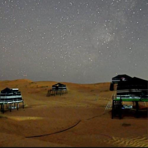 a starry night with two huts in the desert at Varha camp in Ḩawīyah