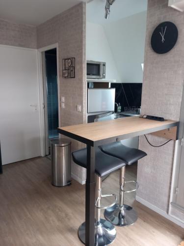 a kitchen with a counter and two bar stools at Studio Alizée accès direct Promenade Marcel Proust in Cabourg