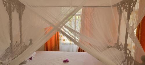 a bedroom with a bed with curtains and a window at Paul's House in Nungwi