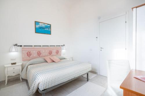a white bedroom with a bed with a pink headboard at Cagliari Central Rooms With Port View in Cagliari