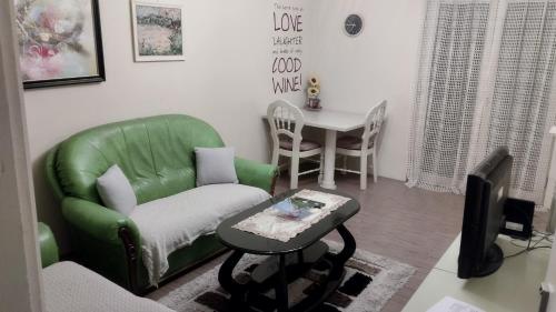 un soggiorno con un divano verde e un tavolo di Apartman Melody a Sombor