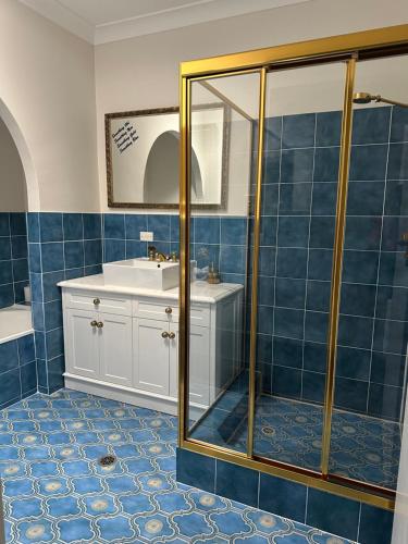 a blue tiled bathroom with a sink and a shower at Palm Beach Bed & Breakfast in Palm Beach