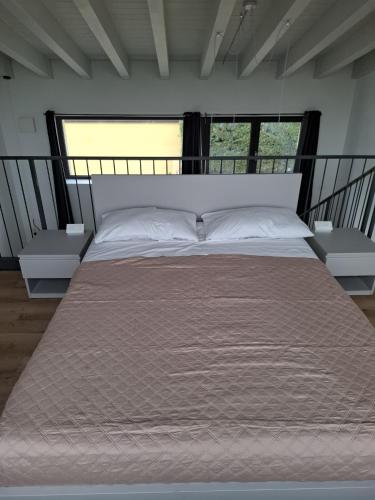 a large bed in a room with two windows at Agriturismo Corte Gaia in Castiglione delle Stiviere