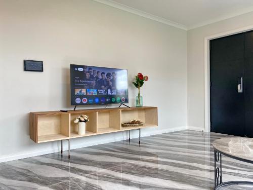 a living room with a flat screen tv on a wooden stand at Brand-New Large house Castlebane Drive in Auckland
