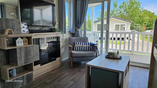 a living room with a tv and a chair and a table at 22 Bryn View - Davies Retreat in Prestatyn