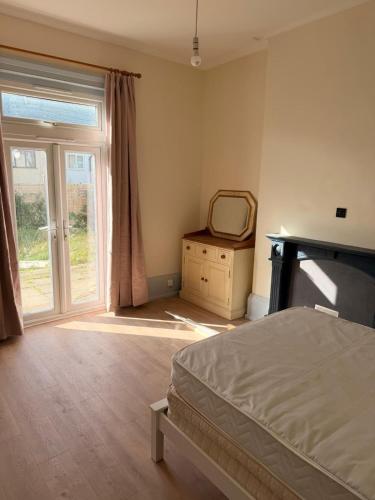 a bedroom with a bed and a mirror and a window at Beautiful Margate Retreat with Log burner, Garden, minutes to beach in Margate