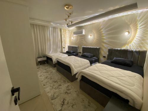 a bedroom with three beds and a wall with lights at Heliopolis Ultra Luxury Panoramic Apt Near Cairo Airport in Cairo