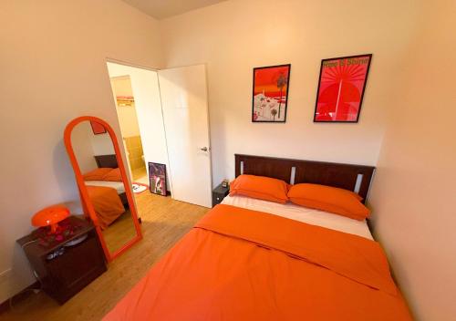 a bedroom with an orange bed and a mirror at The Retrograde at The Crestmont in Manila