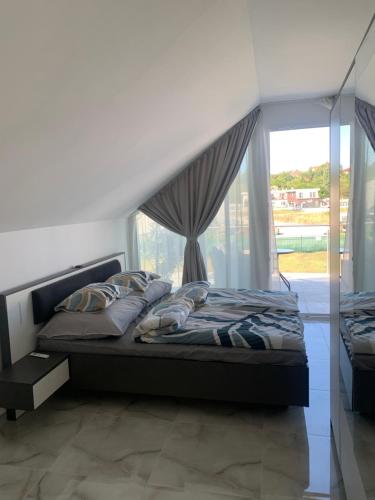 a bedroom with a bed and a large window at Sunset Velence Villa in Velence
