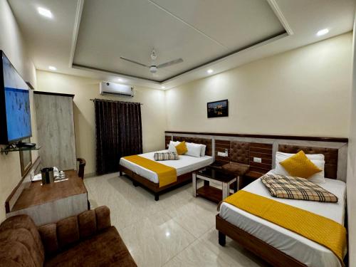 Una habitación de hotel con dos camas y un televisor de pantalla plana. en Sarovar Regency, en Amritsar