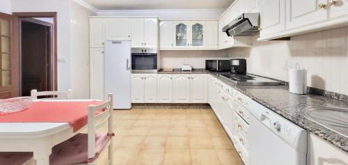 a kitchen with white cabinets and a table in it at AG Piso Isabema a 400m del centro de Carballo in Carballo
