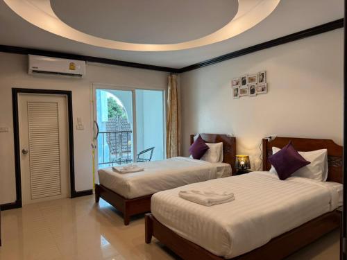 a bedroom with two beds and a large window at SVAH Boutique Patong in Patong Beach