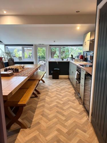 a kitchen with a large wooden table and some windows at The Boho - 4 min walk to beach & town in Bournemouth
