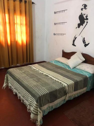 a bedroom with a bed with a blanket on it at Katys Lodge in Ja-Ela
