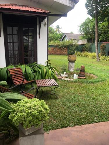 a garden with a bench and a fountain in a yard at Katys Lodge in Ja-Ela