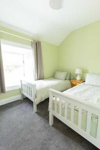 a bedroom with two beds and a window at Making Tracks Farm House in Laois