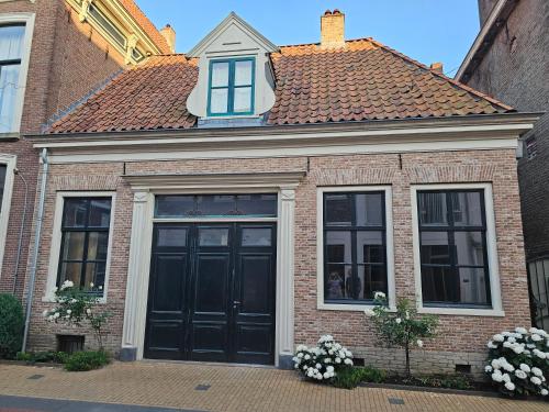 a brick house with a black door and windows at Gasthuis Het Monument in Steenwijk
