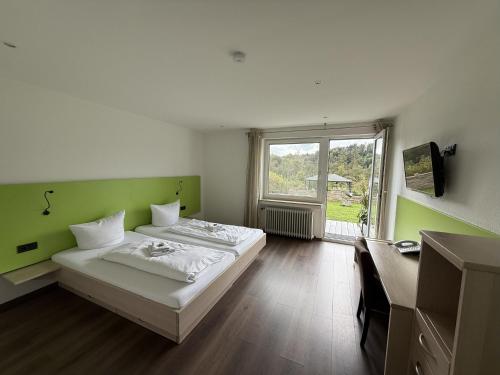 a room with two beds and a desk and a window at Hotel Restaurant Sättele in Steißlingen