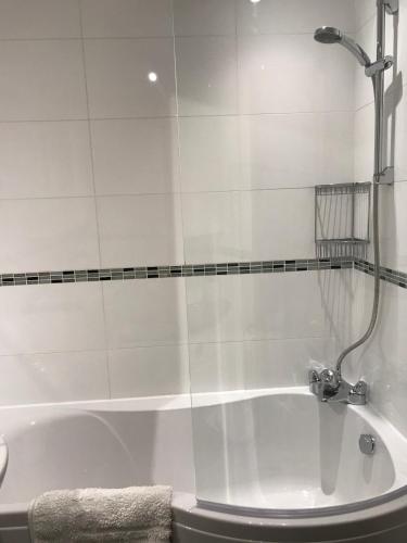 a white bath tub with a shower in a bathroom at Converted Steading in Beach Location in Aberdeen