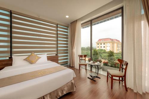 a bedroom with a large bed and a large window at MAI Luxury Hotel Ninh Binh in Ninh Binh