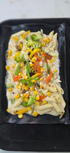 un plato negro de comida con maíz y verduras en Around stays, Tapovan, Rishikesh, en Rishīkesh