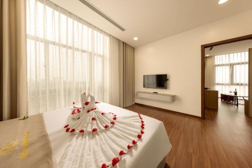 a bedroom with a white bed with a dress on it at MAI Luxury Hotel Ninh Binh in Ninh Binh