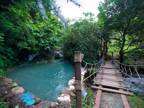 a suspension bridge over a river in a forest at Green River Camp in Rishīkesh