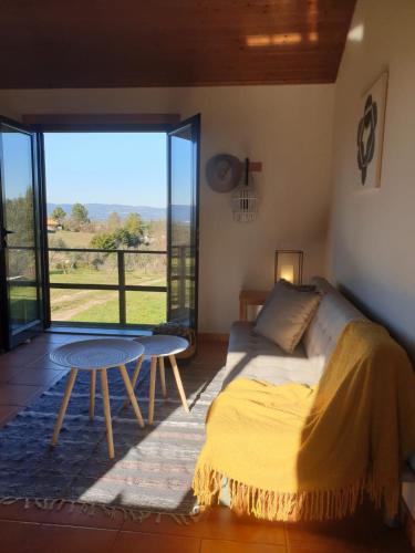 a bedroom with a bed and a table and a large window at Quinta de Natureza in Nabais