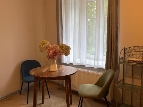 a vase of flowers on a table in front of a window at The 7th Apartment in Cēsis