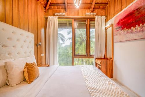 sypialnia z łóżkiem i dużym oknem w obiekcie Rainforest Resort w mieście Port Blair