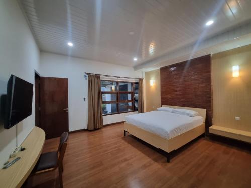 a bedroom with a bed and a desk and a television at Serambi Buya Syariah 5 BR in Jetis