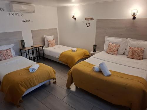 a room with three beds with yellow sheets at Hôtel Le Médiéval- Parking inclus in Aigues-Mortes