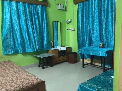 kolkataにあるAirport accommodation!の青いカーテンと鏡のある寝室