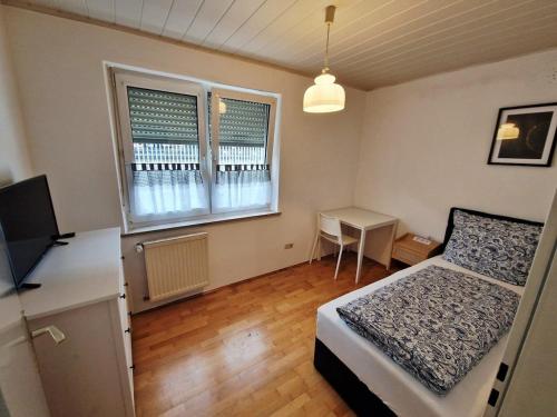 a bedroom with a bed and a desk and a television at Family Suite del Pueblo in Weiden