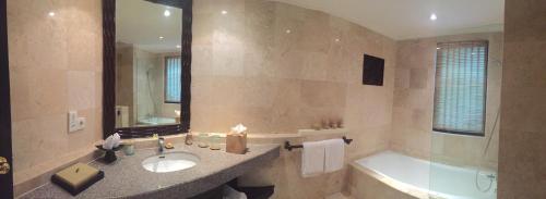 y baño con lavabo, bañera y espejo. en Spa Village Resort Tembok Bali - Small Luxury Hotels of the World, en Tejakula