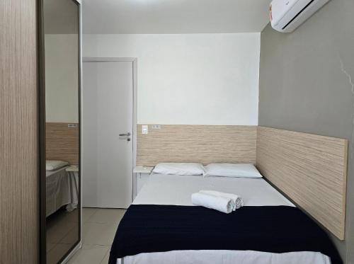 ein kleines Schlafzimmer mit einem Bett mit zwei Handtüchern darauf in der Unterkunft Areias do Mar Aconchegante e Tranquilo com Varanda in Barra de São Miguel