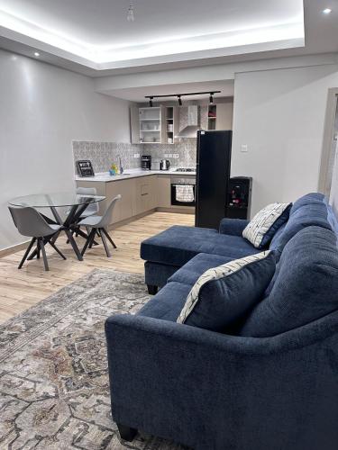 een woonkamer met een blauwe bank en een keuken bij Cloud9 suites - Westlands Road in Nairobi