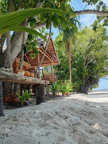 a resort on the beach with trees and sand at Naviza Homestay in Kepulauan Fam