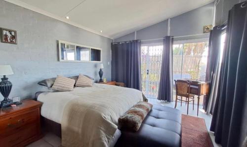 a bedroom with a large bed and a chair and a desk at La Santos Beach view Villa with 3 Bed , 3 Bath, Jacuzzi, Sea view in Mossel Bay