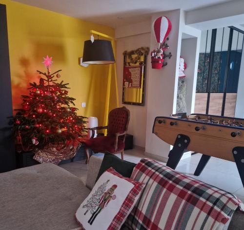 ein Wohnzimmer mit einem Weihnachtsbaum und einer Tischtennisplatte in der Unterkunft MAGNIFIQUE VILLA LUXE COSY POPPIES HOLIDAY - Noël à la Mer, Flipper, Baby-foot, SPA, Jardin Illuminé, Plage Riva Bella à 300m, Magie de Noël, Tout Confort, Idéale Familles, Groupes & EVG EVJF, Proche Cabourg, Week-end & Courts Séjours ! in Ouistreham