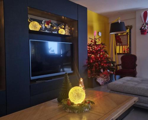 a living room with a television and a christmas tree at MAGNIFIQUE VILLA LUXE COSY POPPIES HOLIDAY - Noël à la Mer, Flipper, Baby-foot, SPA, Jardin Illuminé, Plage Riva Bella à 300m, Magie de Noël, Tout Confort, Idéale Familles, Groupes & EVG EVJF, Proche Cabourg, Week-end & Courts Séjours ! in Ouistreham