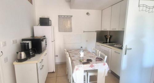 une cuisine avec une table avec des chaises et un réfrigérateur dans l'établissement Appartement cosy vue mer, à Grosseto-Prugna